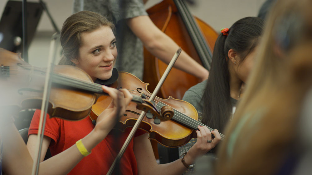 Students in orchestra playing violins